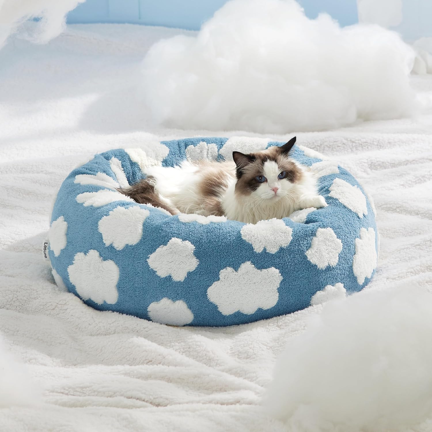 Gato descansando cómodamente en cama donut antiestrés azul